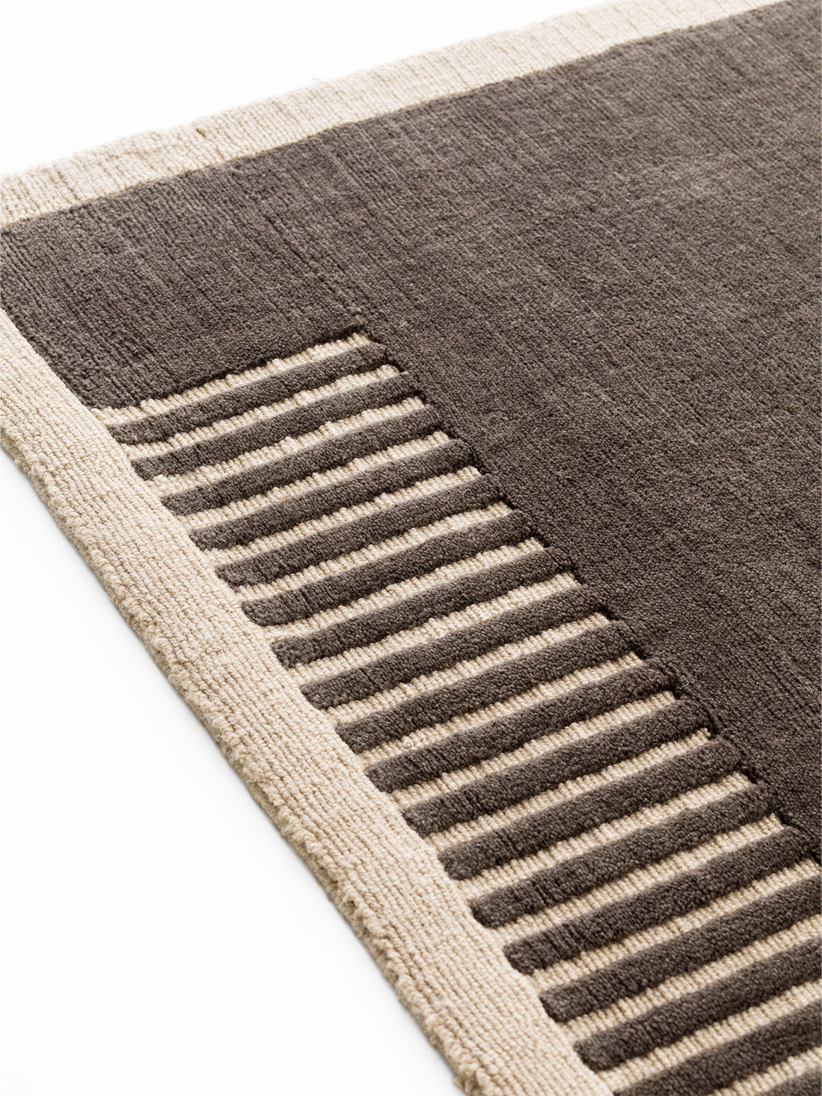 Close-up of a brown wool rug with a cream border and textured