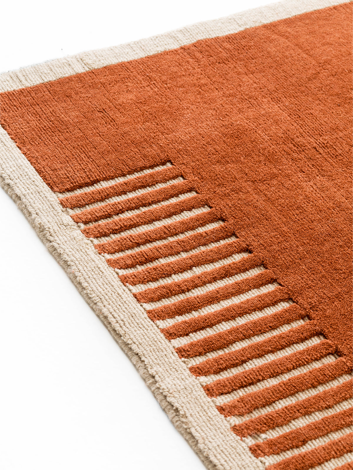 Close-up of terracotta and cream woven wool rug with raised striped border