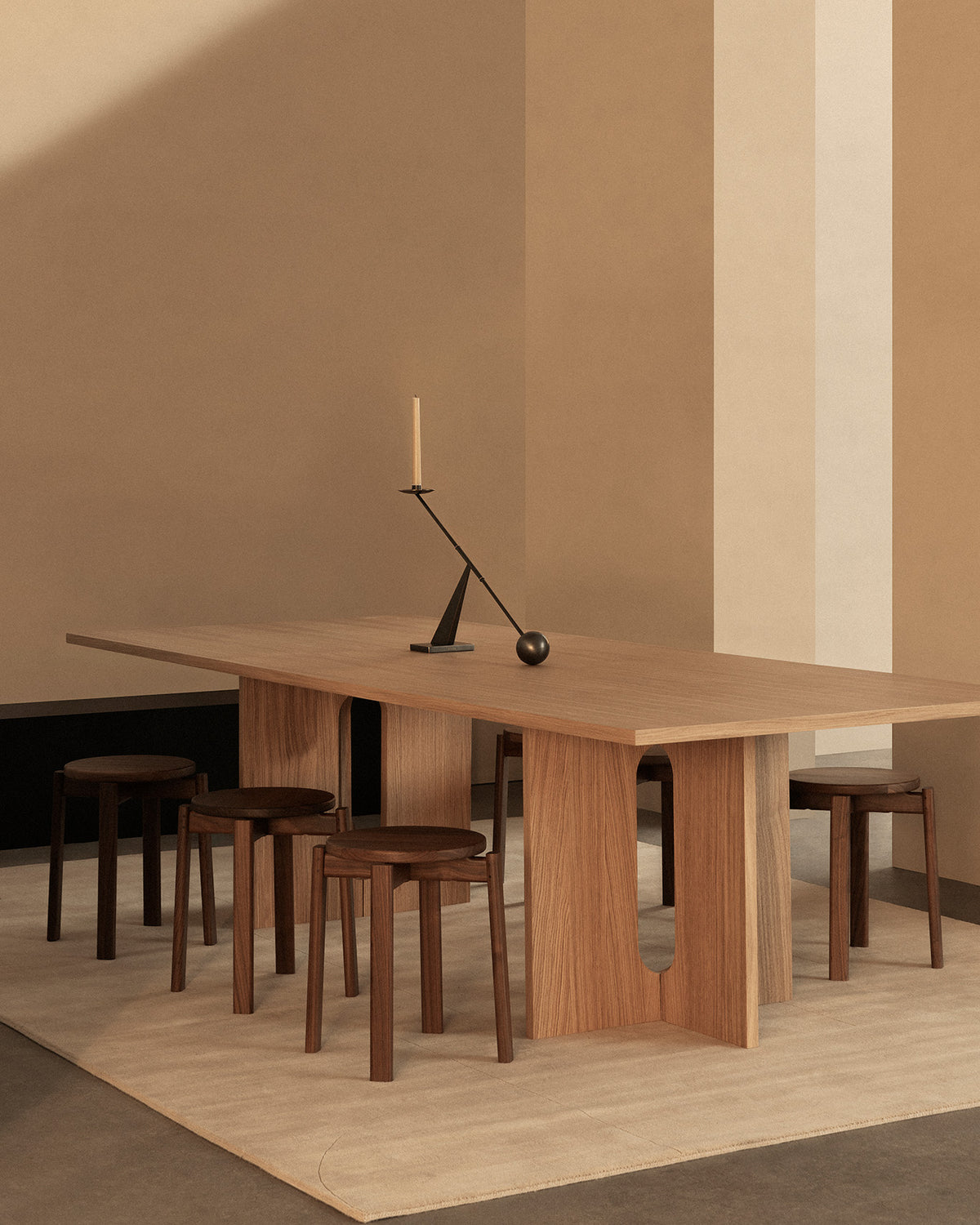 Minimalist wooden dining table with matching round stools, dark metal balancing