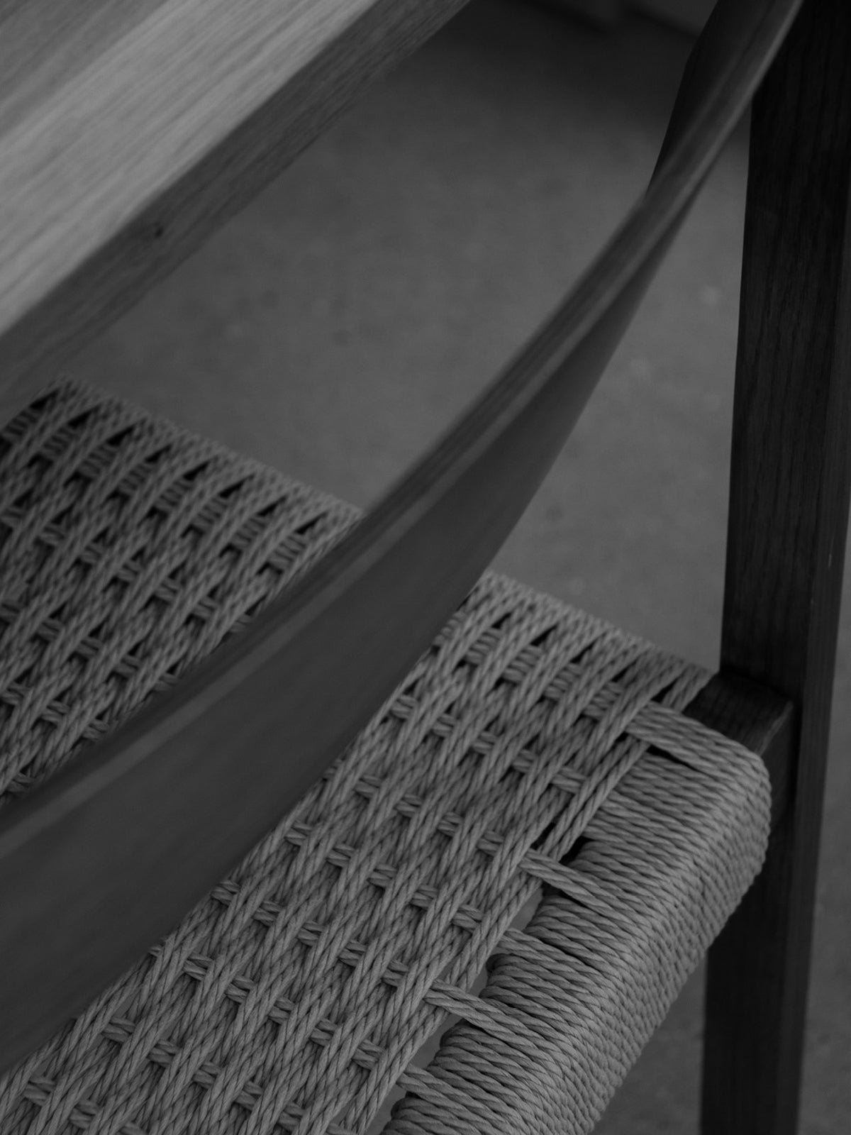 Close-up of woven natural rope seat and curved wooden armrest on a