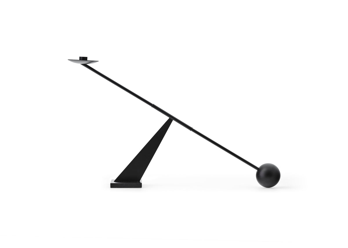 Black minimalist balancing table lamp with angled metal arm, triangular base and
