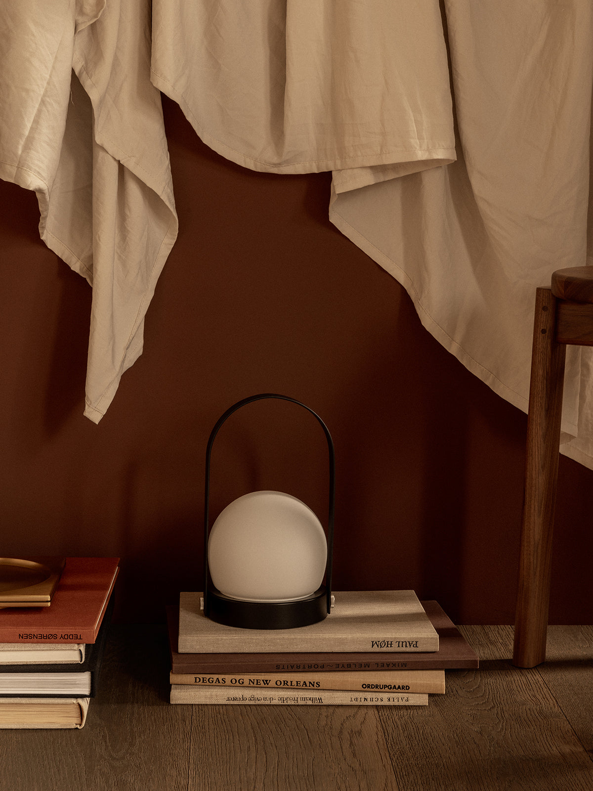 Matte black portable lamp with round white glass globe on stacked books,