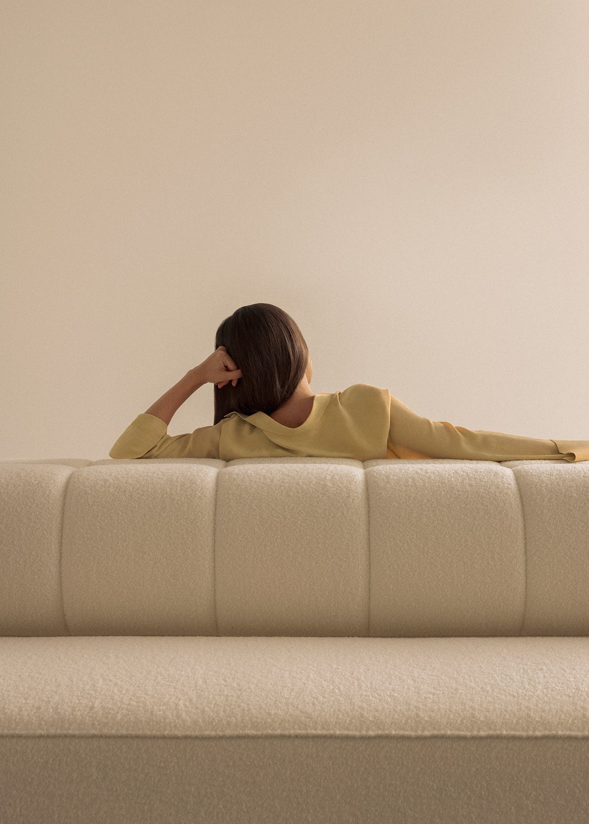 Cream boucle sofa back with a person reclining in a pale yellow