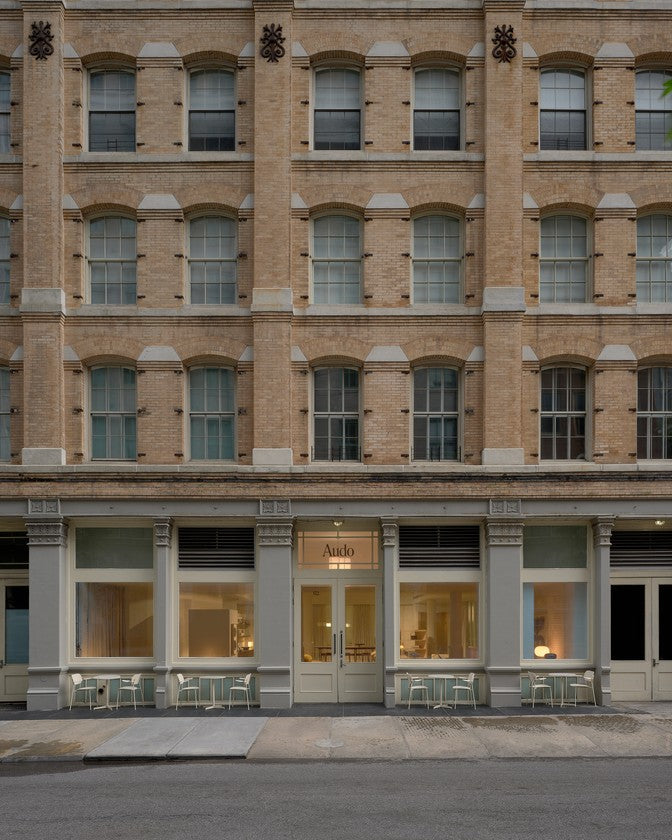 Street-level view of a pale brick building with arched windows and a
