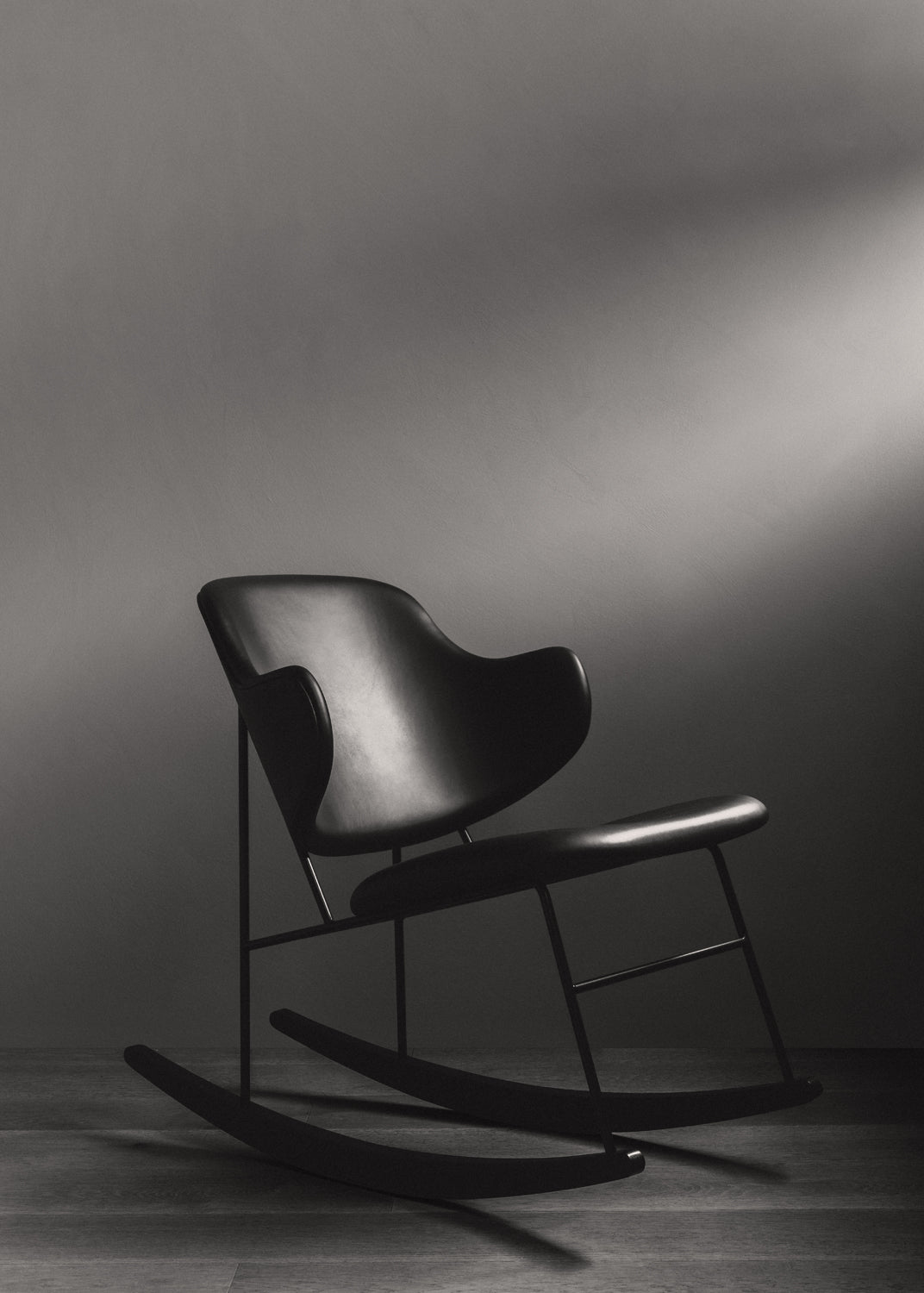 Matte black leather rocking chair with curved shell seat and slim metal