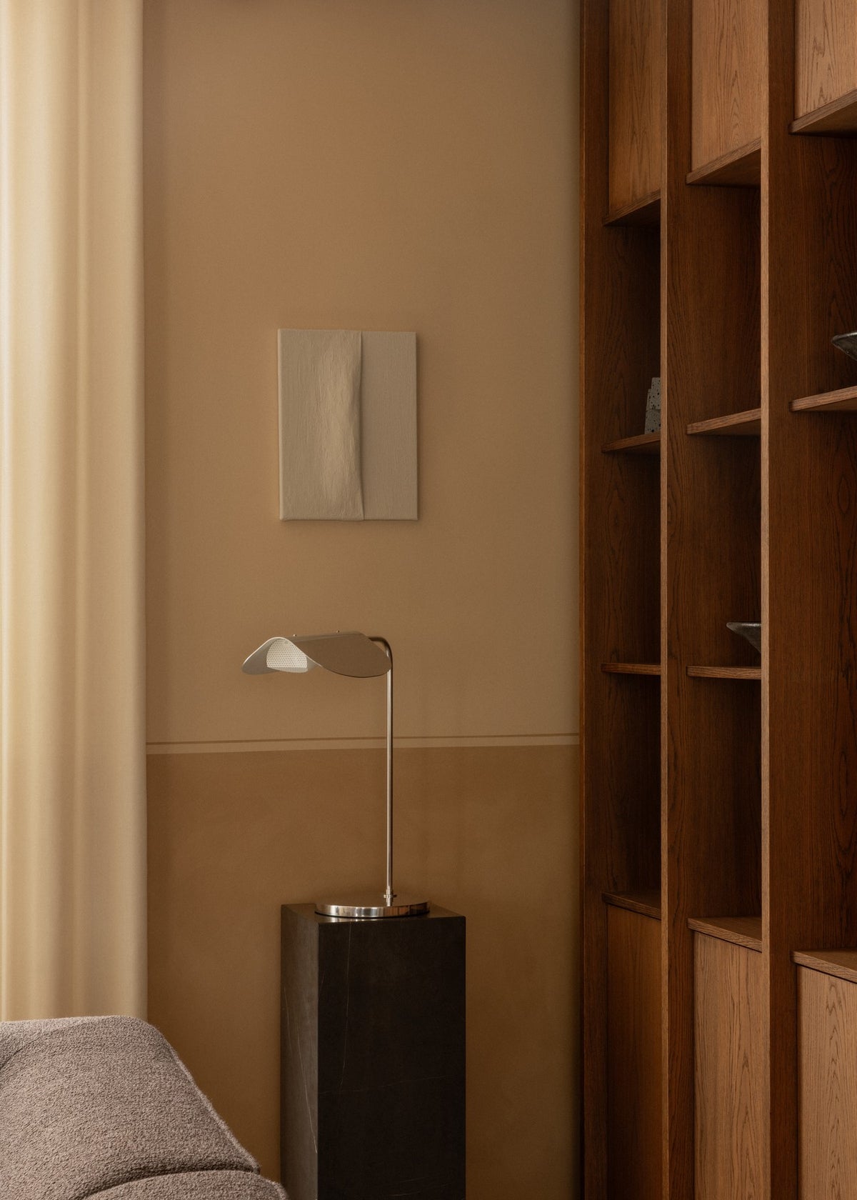 Brass desk lamp with curved shade on a dark stone pedestal beside