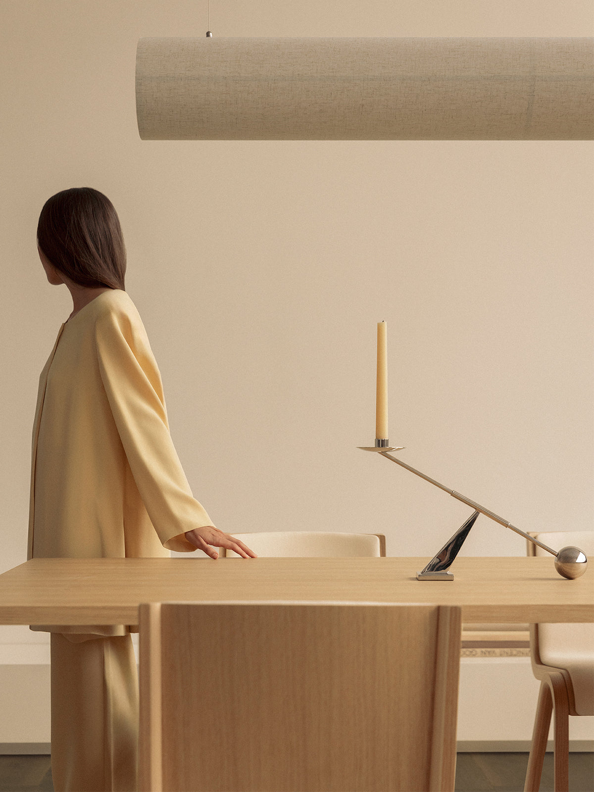 Minimal beige fabric pendant light above wooden table with chrome balancing cand