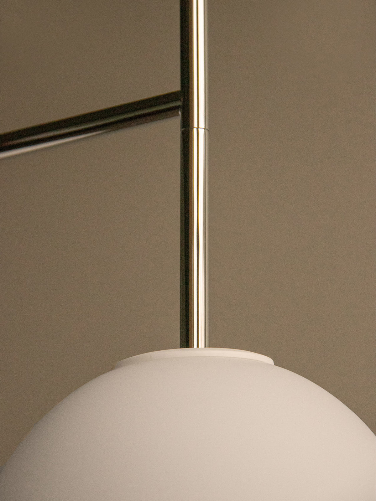 Close-up of a matte white glass globe pendant lamp with polished brass