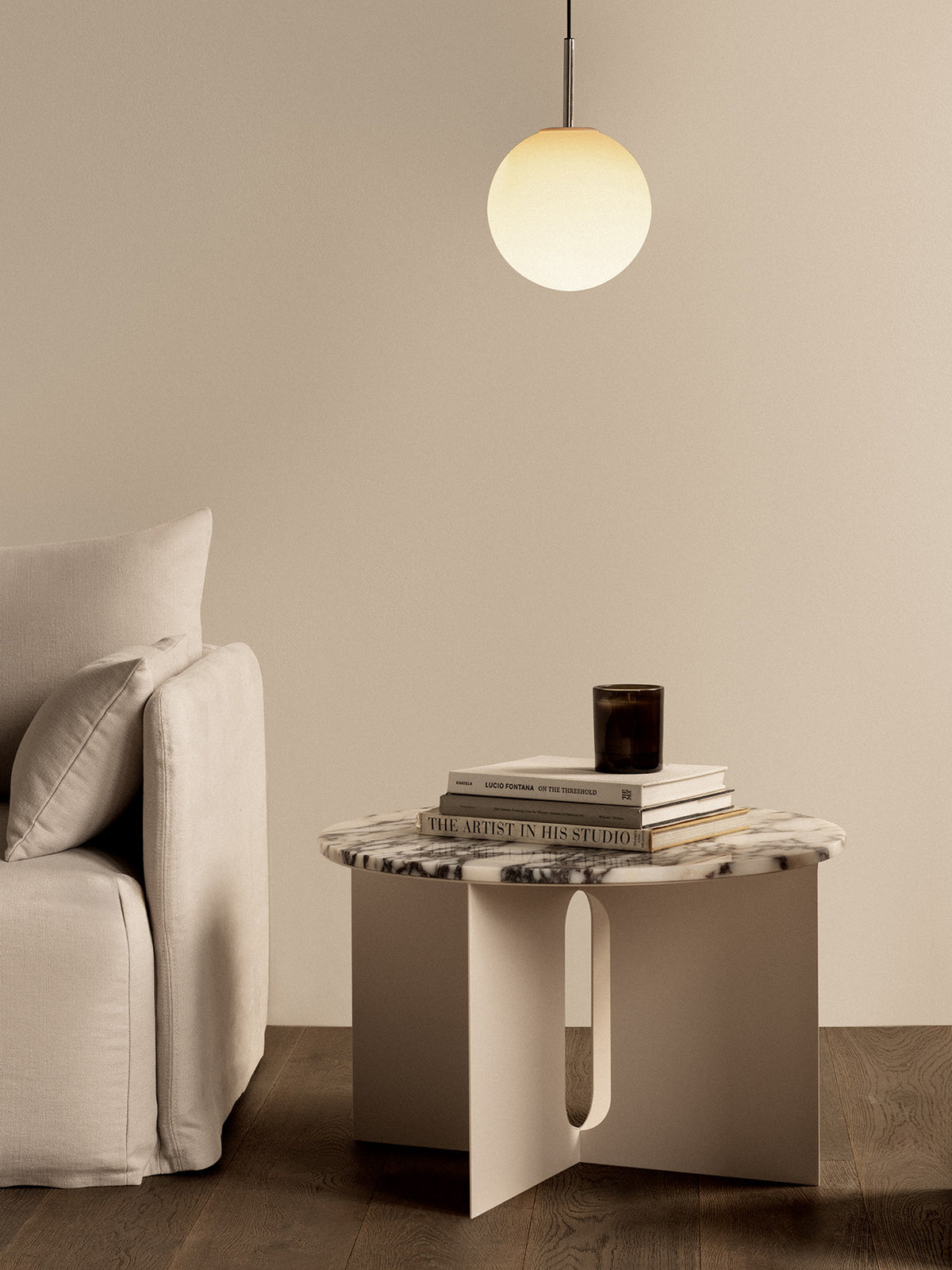 Minimal beige living room scene with a white marble-top side table, stacked