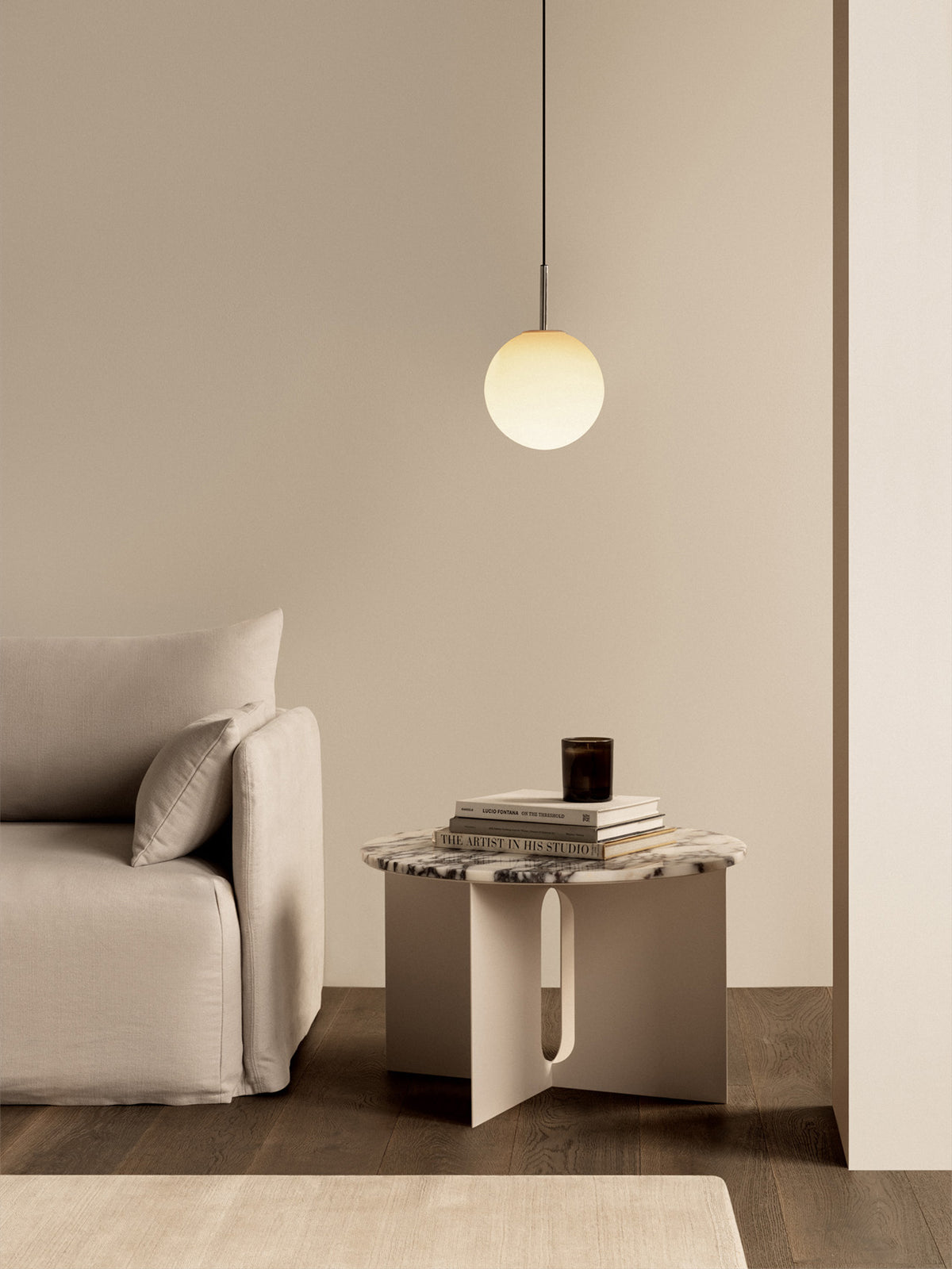 Minimal beige living room with a round frosted glass pendant light, marble-top