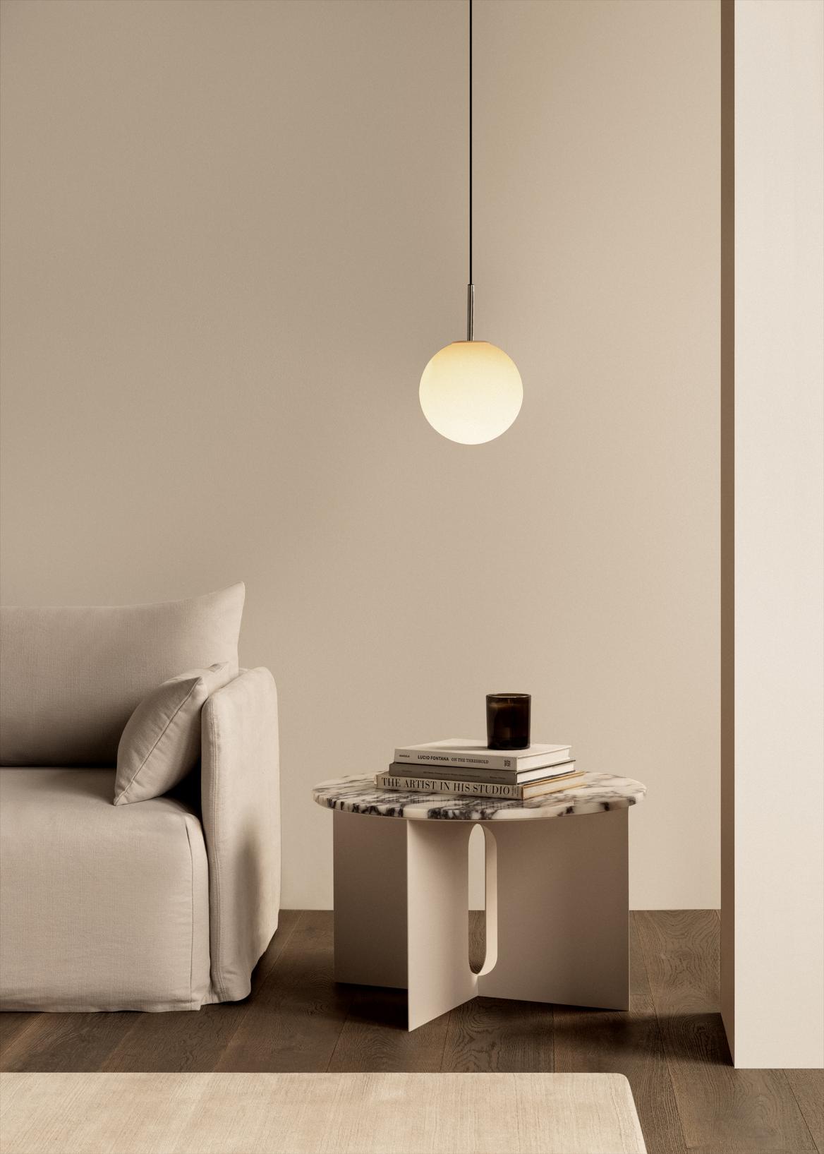 Beige minimalist living space with a round frosted glass pendant, marble-topped