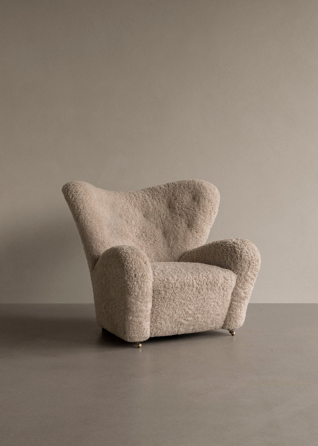 Beige boucle upholstered lounge chair with rounded wingback, plush curved arms a