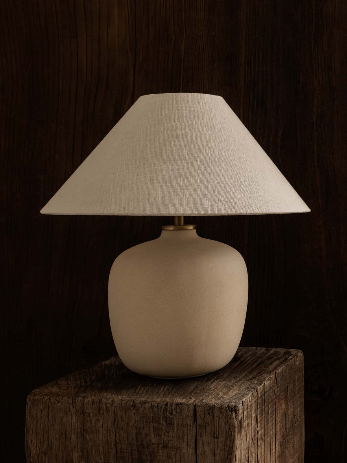 Beige ceramic table lamp with wide linen shade on rustic dark wood