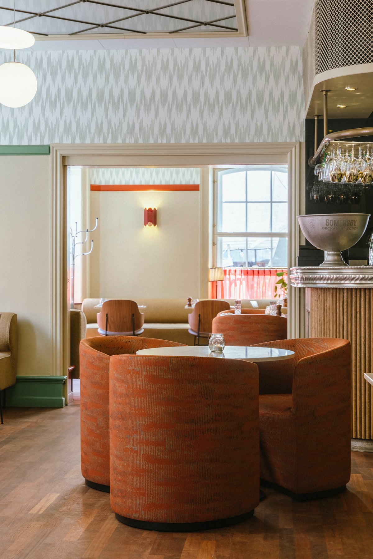 Round orange upholstered booth seating around a small white table in a