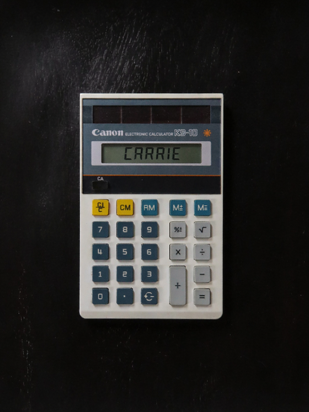 Vintage Canon K9-10 white calculator with blue and gray keys, yellow function