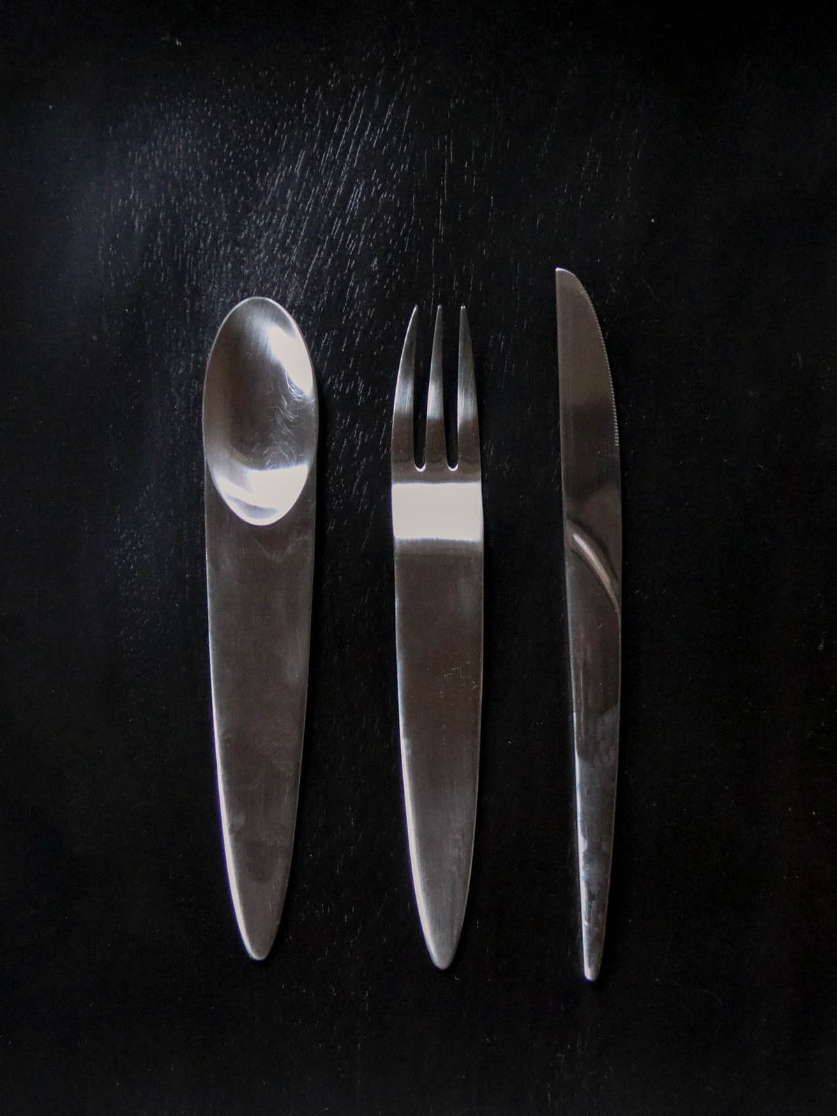 Stainless steel spoon, three-prong fork and serrated knife with tapered handles