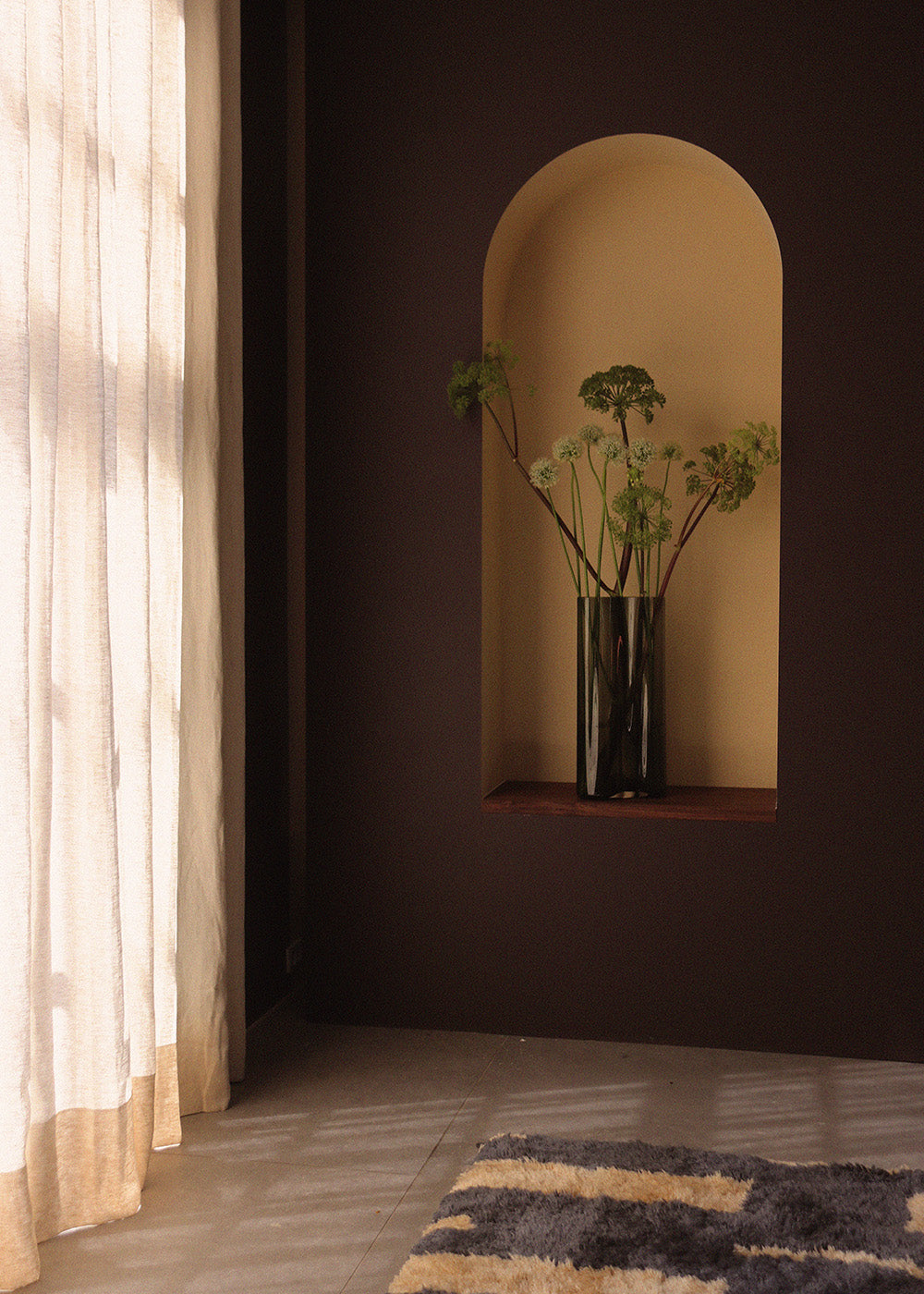 Arched wall niche painted warm beige with dark brown surround, holding a