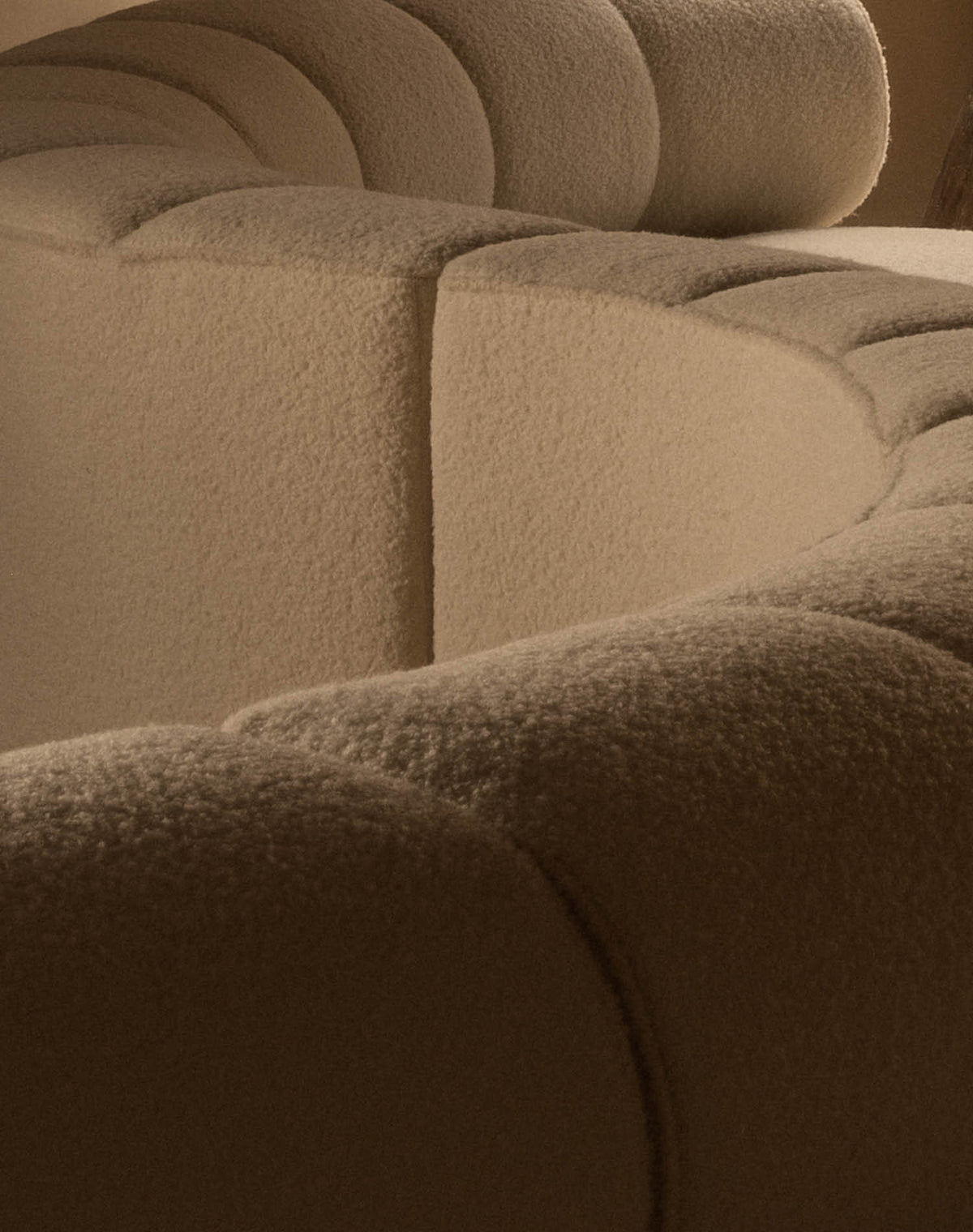 Close-up of a beige boucle upholstered sofa showing rounded, scalloped cushions