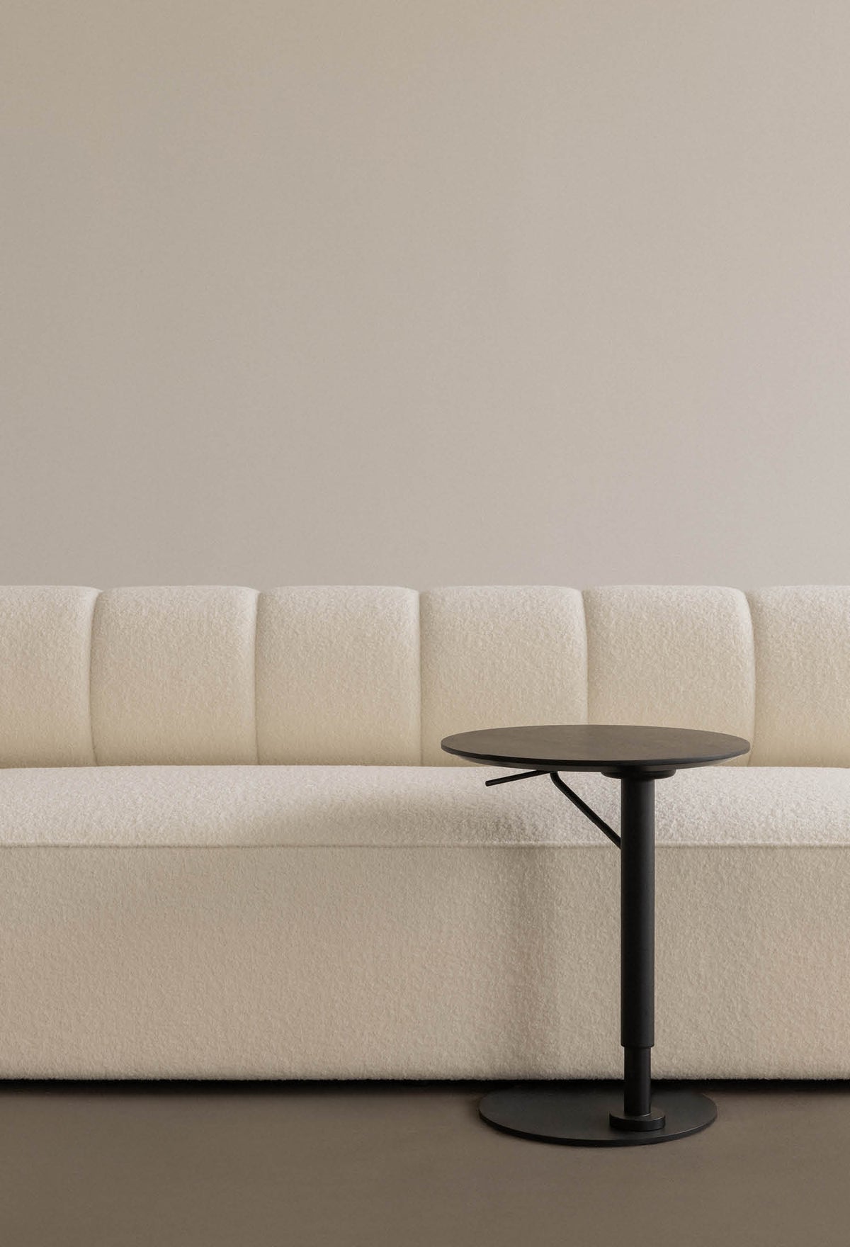 Cream boucle upholstered sofa with vertical channeling and a round black metal