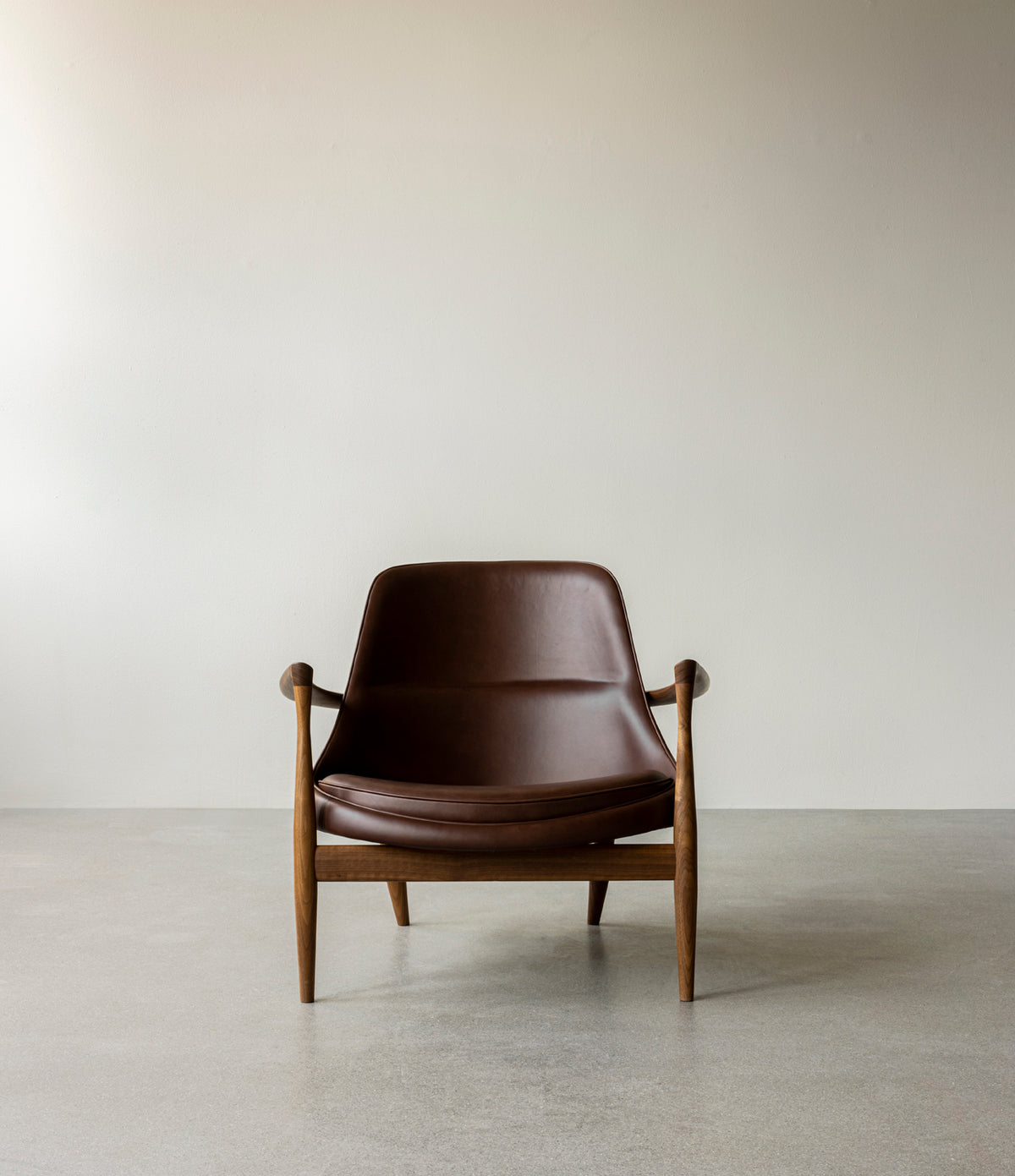 Mid-century lounge chair with dark brown leather seat and curved walnut frame