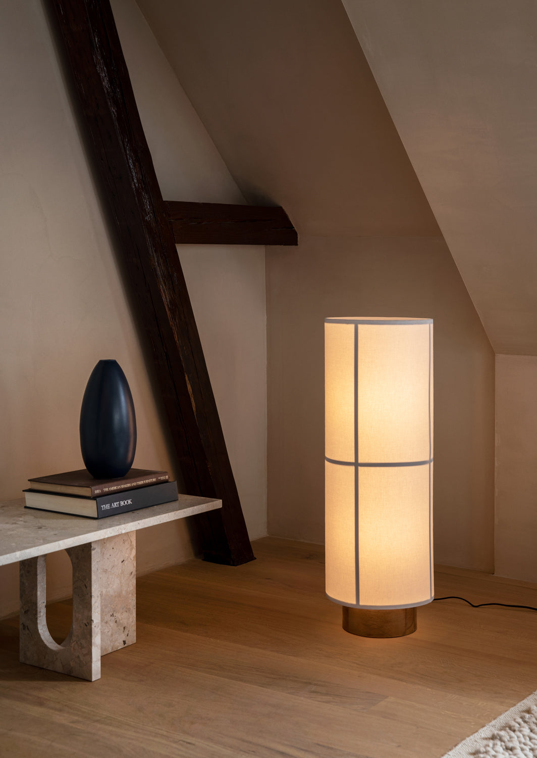 Tall cylindrical fabric floor lamp with warm light, slim vertical seams and