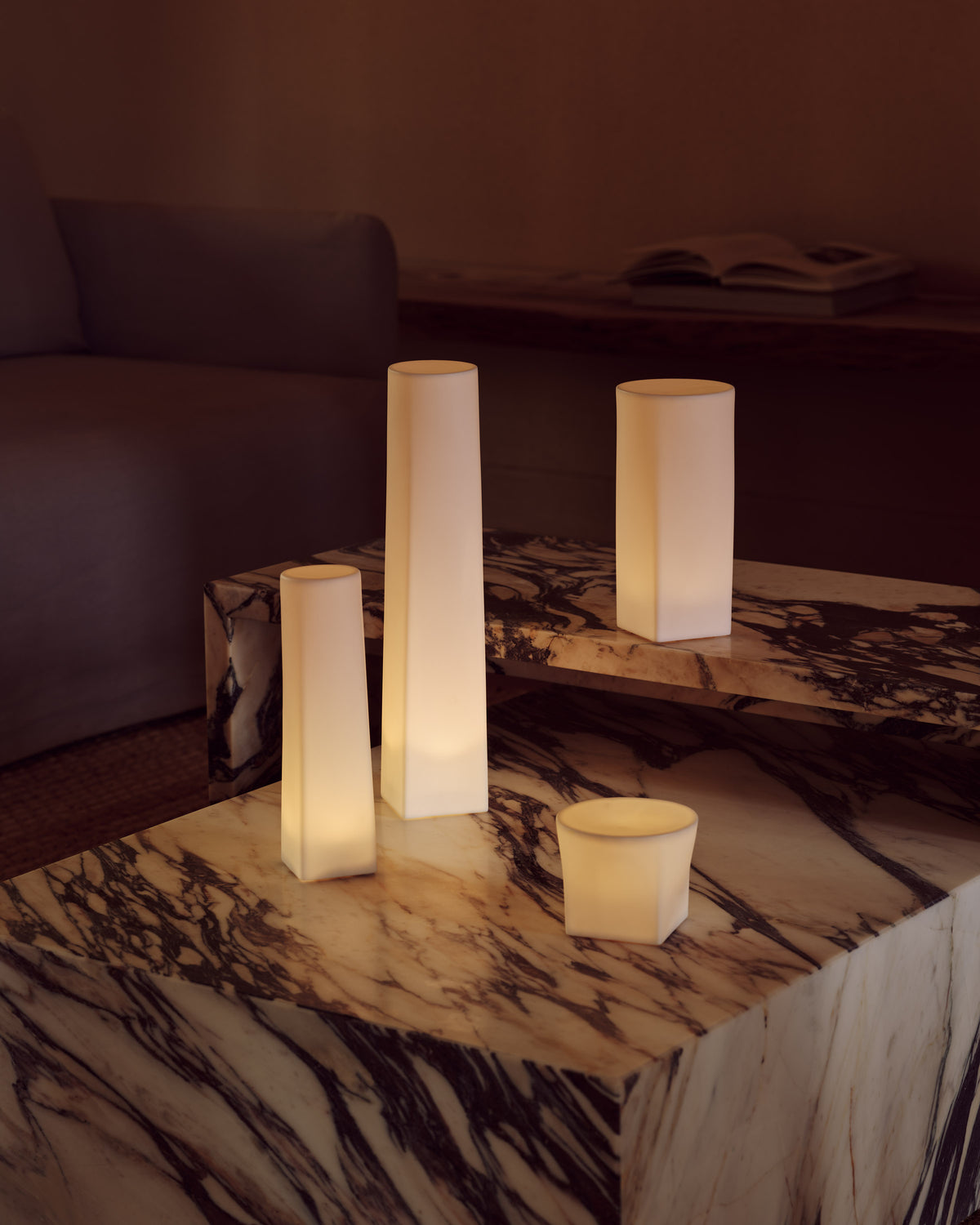 Glowing white cylindrical and rectangular LED lamps on a cream-and-brown veined