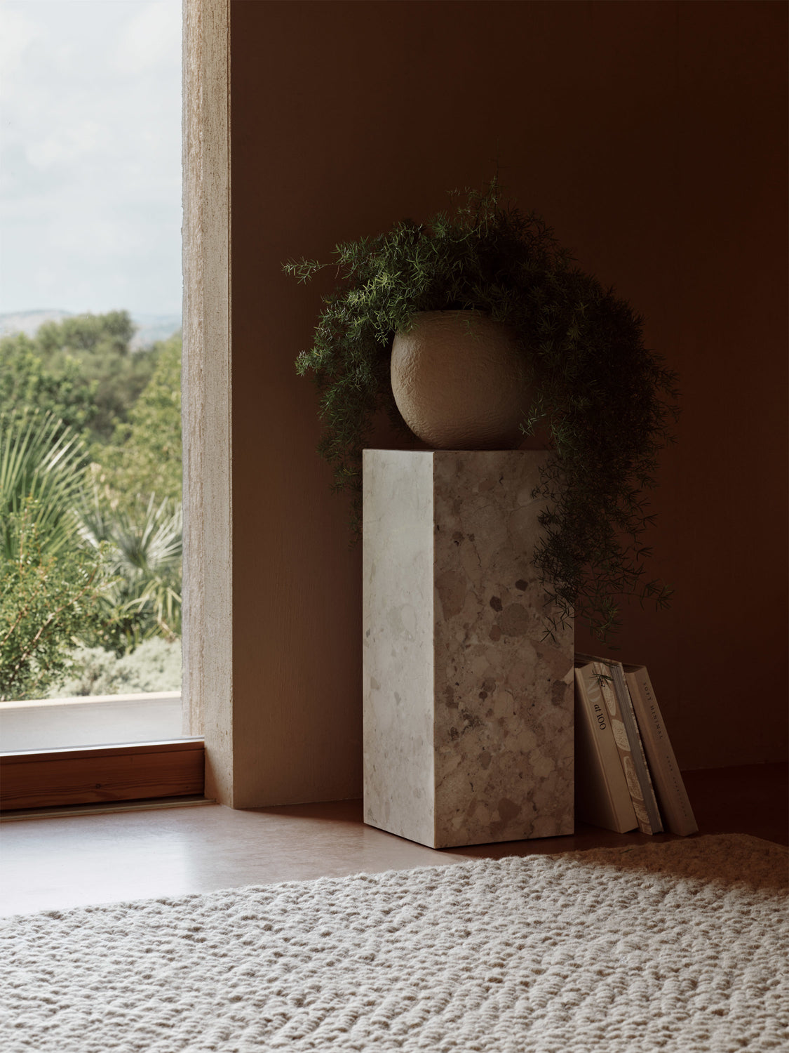 Tall rectangular light-grey marble pedestal with a textured round beige planter