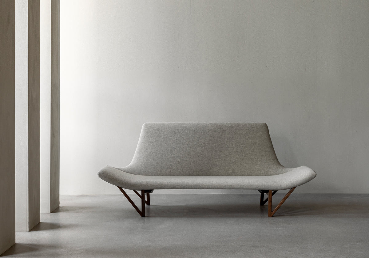 Minimal light grey upholstered lounge sofa with curved seat and wooden angled