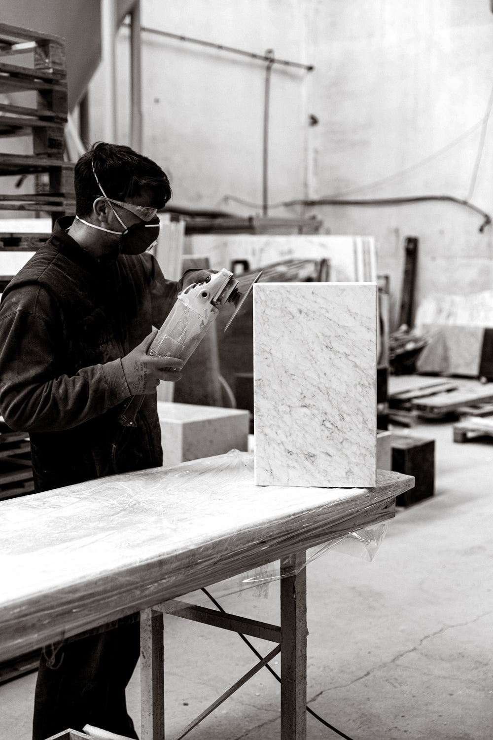 Worker wearing mask and goggles using an angle grinder to finish a