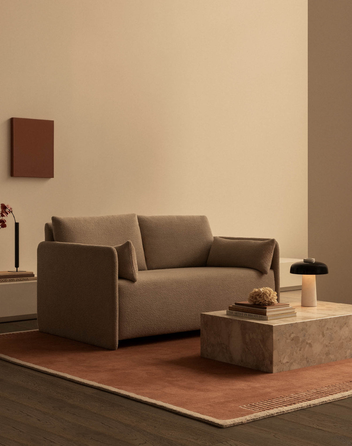 Beige upholstered two-seater sofa with soft rounded arms, terracotta rug, marble