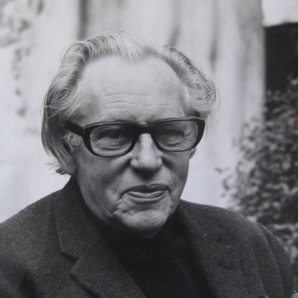 Black-and-white close-up of an older person wearing thick black rectangular glas