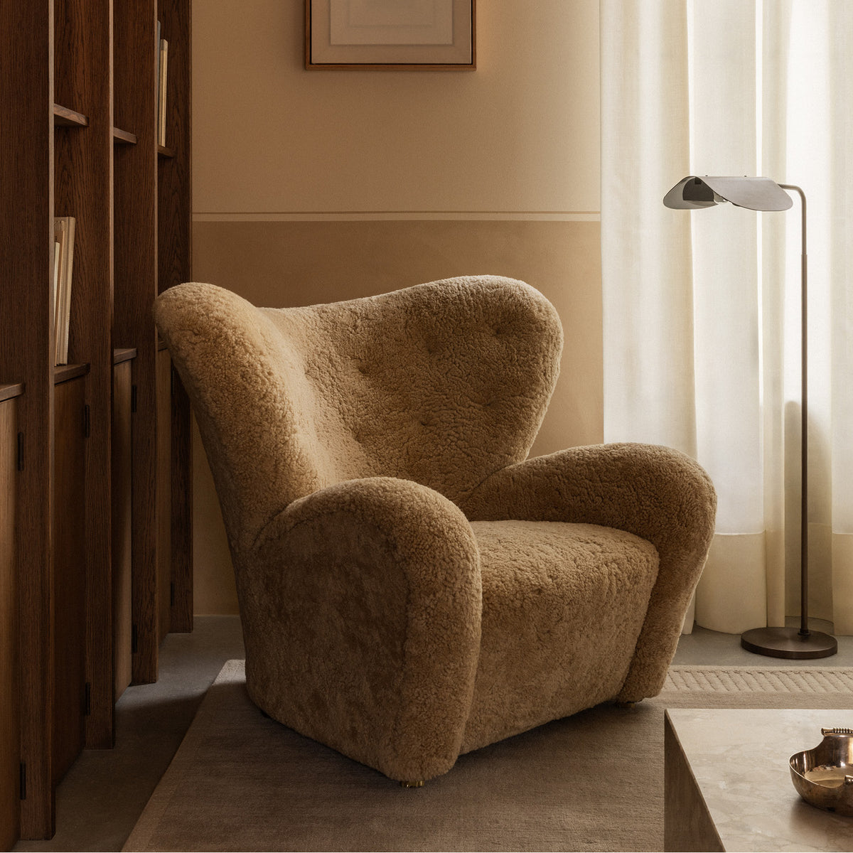 Plush camel-colored sheepskin armchair with rounded wingback and armrests beside