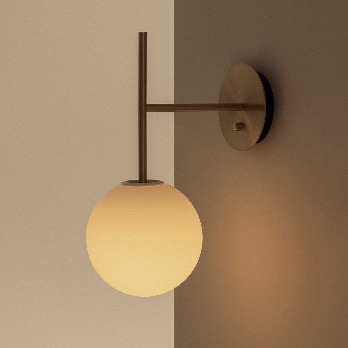 Brass wall lamp with an opal glass globe diffuser mounted on a
