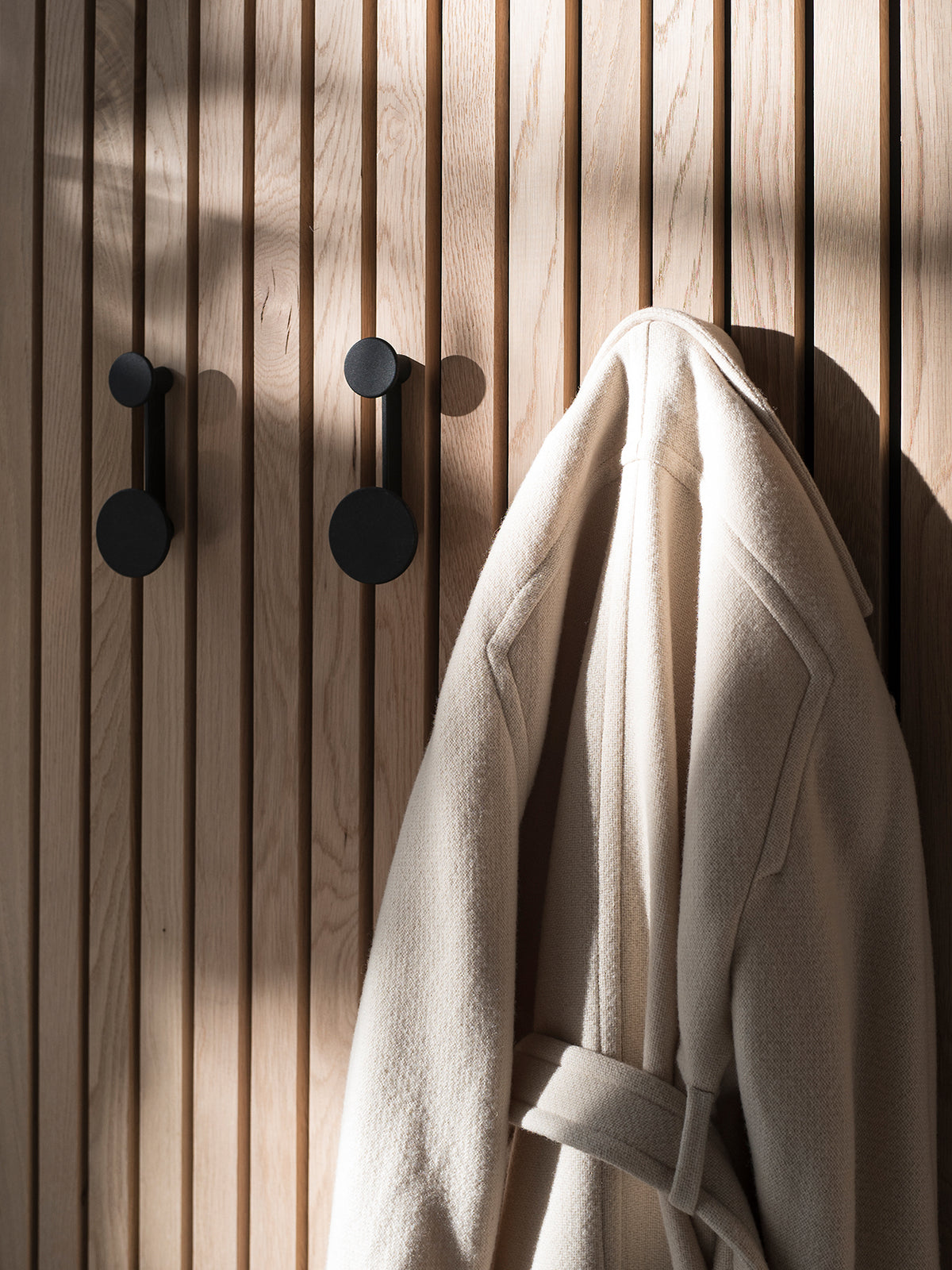Afteroom Coat Hanger in Schwarz an einer hellen Eichen-Lamellenwand mit einem cr