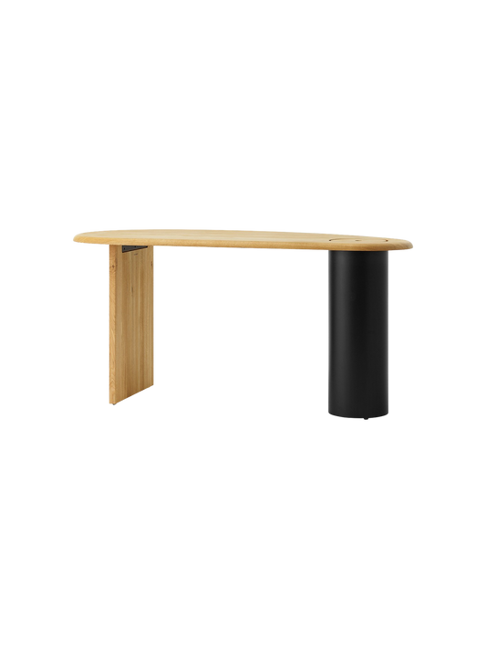 The Eclipse Desk in natural oiled oak, seen at an angle, highlighting its asymmetrical top, flat leg, and black column leg.