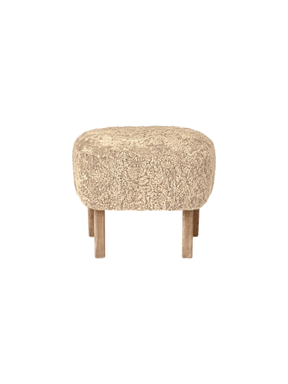 A front-facing view of the Ingeborg Ottoman. It has a fluffy, honey-coloured sheepskin top and four light oak legs.