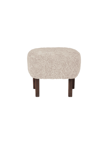 A front view of the Ingeborg Ottoman, upholstered in fluffy, off-white Moonlight sheepskin with four dark stained oak legs.