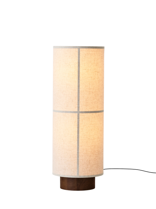 Hashira Floor Lamp in raw linen with a cylindrical shade and wooden base, shown glowing against a black background.