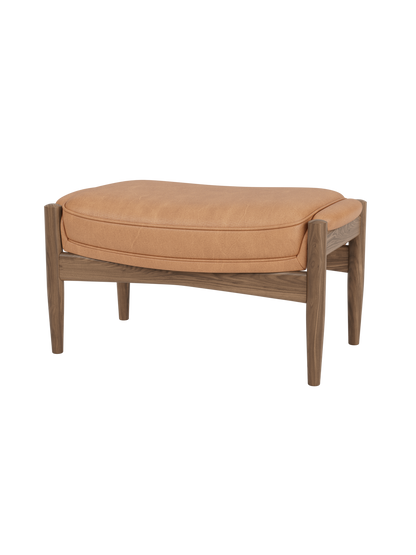 The Seal Ottoman in walnut wood with Dunes Camel leather upholstery, highlighting its organic mid-century silhouette.