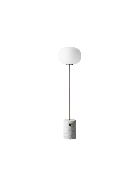 The JWDA Floor Lamp with a cylindrical white Carrara marble base, a bronzed brass stem, and an elliptical white glass shade.