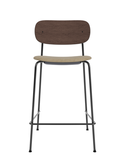 Co Counter Chair in dark stained oak and black steel with an upholstered seat in bouclé fabric against a black background.