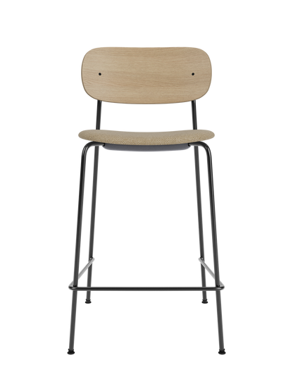 Co Counter Chair in natural oak and black steel featuring an upholstered seat in bouclé against a black background.