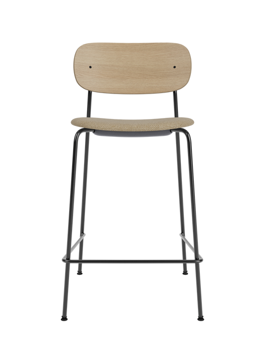 Co Counter Chair in natural oak and black steel featuring an upholstered seat in bouclé against a black background.