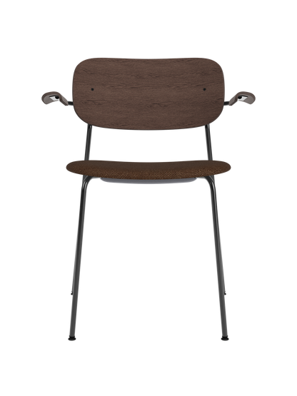 Co Dining Chair with armrests, featuring a dark stained oak back and brown bouclé upholstered seat on a black steel frame.