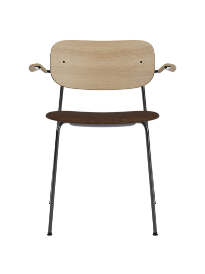 Co Dining Chair with natural oak back and brown bouclé upholstered seat on a black steel frame with armrests.