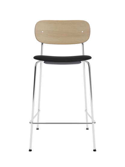 Co Counter Chair in natural oak with a black upholstered seat and chrome steel frame against a black background.