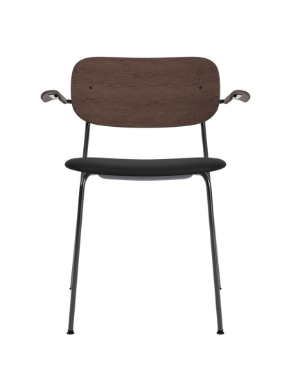 Co Dining Chair with armrests, featuring a dark stained oak backrest and black upholstered seat on a sleek black frame.