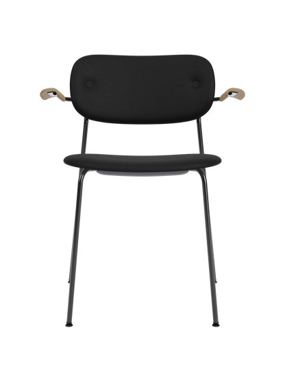 Fully upholstered black Co Dining Chair with natural oak armrests and a sleek black powder-coated steel frame.