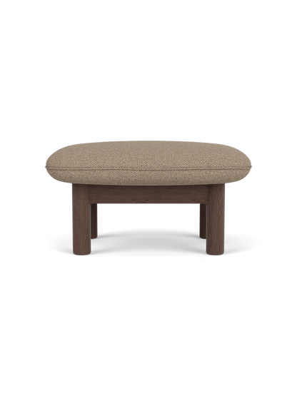 Side view of the Brasilia Ottoman in dark stained oak with a textured Logan Flint textile cushion, on a black background.
