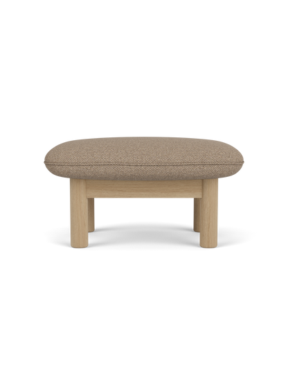 A side view of the Brasilia Ottoman, featuring a textured Logan Flint upholstered cushion and a solid natural oak wood frame.